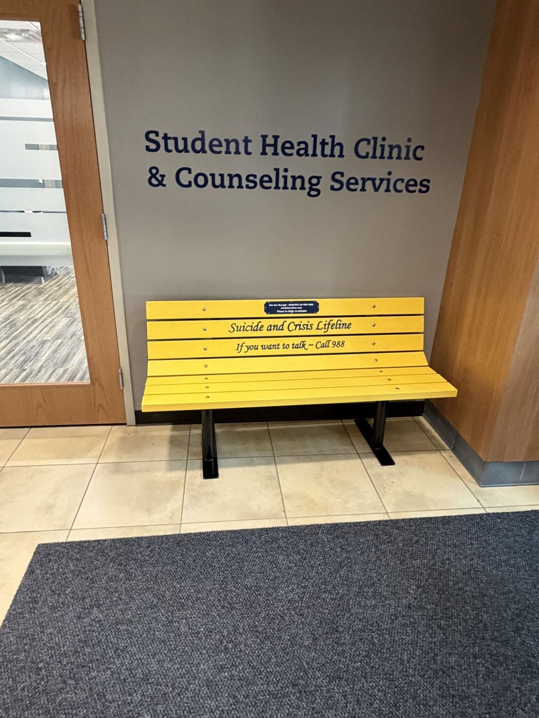 Yellow Suicide Awareness Bench displaying the 988 lifeline number at SDSU Student Health Clinic & Counseling Services